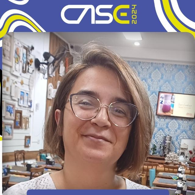 Oie, sou a Elaine, tutora, uma mulher de 1,53m, cabelos curtos, reflexo loiro, estou vestida com uma blusa branca.
